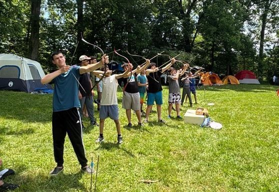 Campers lined up shooting traditional bows
