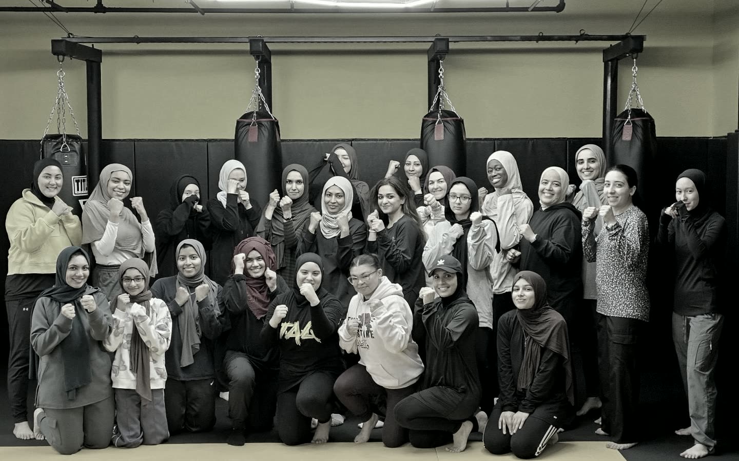 The women's kickboxing class together in front of the heavy bags
